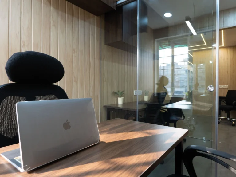 Laptop on a desk in a glass-partitioned private cabin at Linked Offices, Kolkata