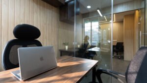 Laptop on a desk inside a glass-partitioned cabin at Linked Offices, Kolkata