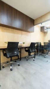 Row of private cabin workstations with ergonomic chairs and wood-panelled walls at Linked Offices, Kolkata