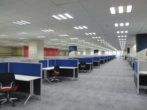 Open-plan office floor with blue partition desks and rows of workstations